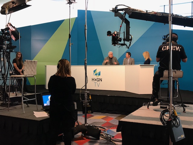 Three people sitting at a dais while being filmed
